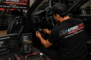 Technician testing a vehicle audio system with a handheld device Technician testing a vehicle audio system with a handheld device