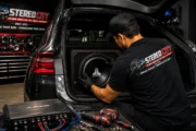 Technician installing a subwoofer and amplifier in the back of an SUV Technician installing a subwoofer and amplifier in the back of an SUV